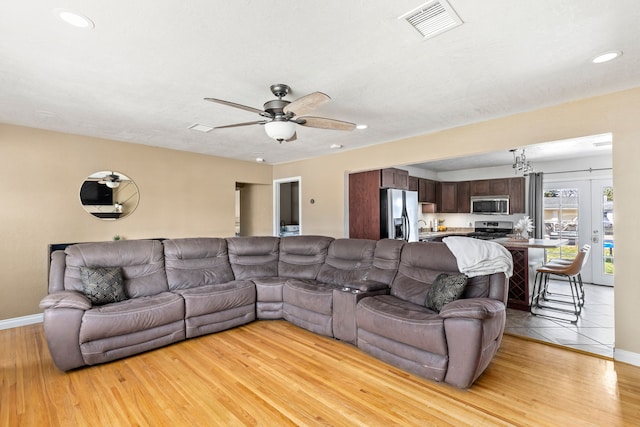 living area with a ceiling fan, baseboards, visible vents, and light wood-style floors