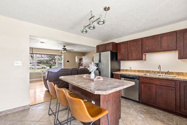 kitchen featuring a kitchen island, dishwasher, a sink, fridge with ice dispenser, and open floor plan