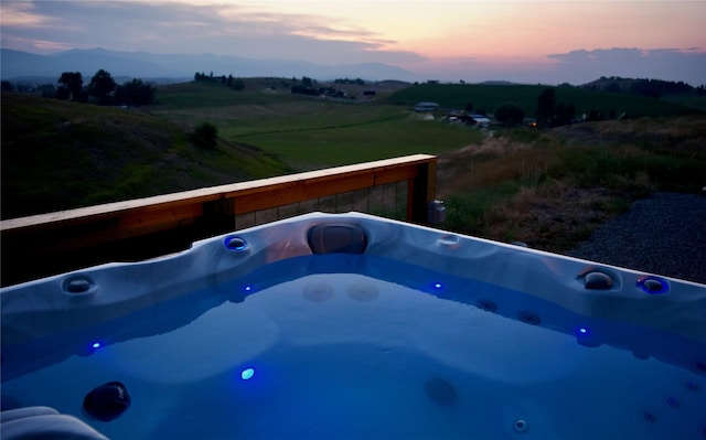 288 Costich Lake Rd, Eureka, MT 59917 - pool at dusk featuring a hot tub, a mountain view, and a rural view