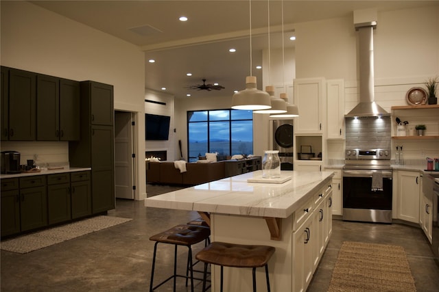 288 Costich Lake Rd, Eureka, MT 59917 - kitchen with stacked washer / dryer, wall chimney range hood, recessed lighting, tasteful backsplash, and stainless steel range with electric cooktop