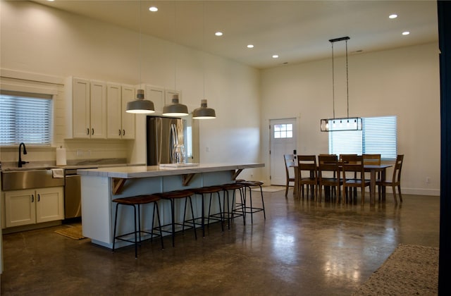kitchen with a high ceiling, recessed lighting, a center island, a sink, and appliances with stainless steel finishes