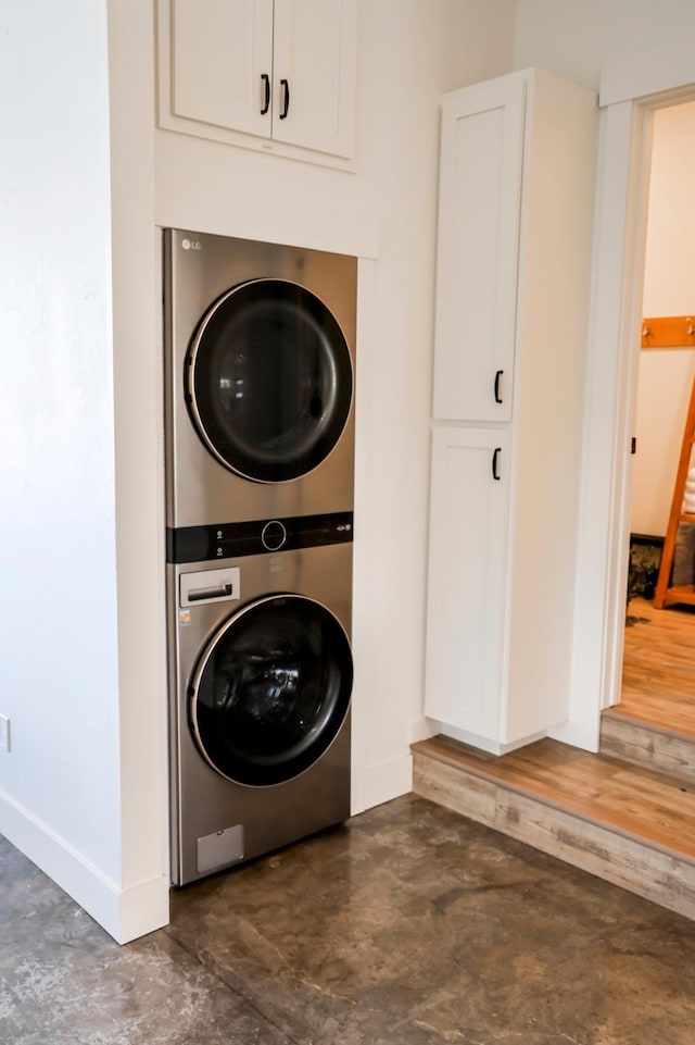 clothes washing area with laundry area, baseboards, and stacked washer / dryer