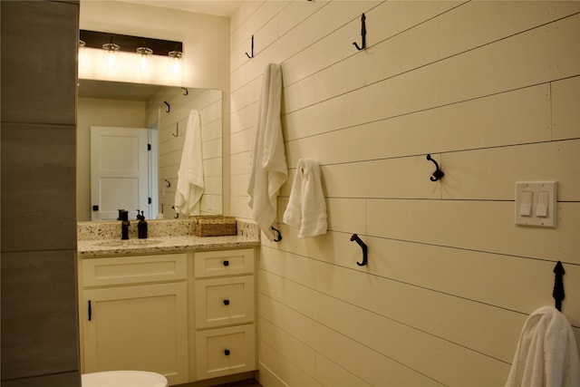 half bath featuring wood walls and vanity
