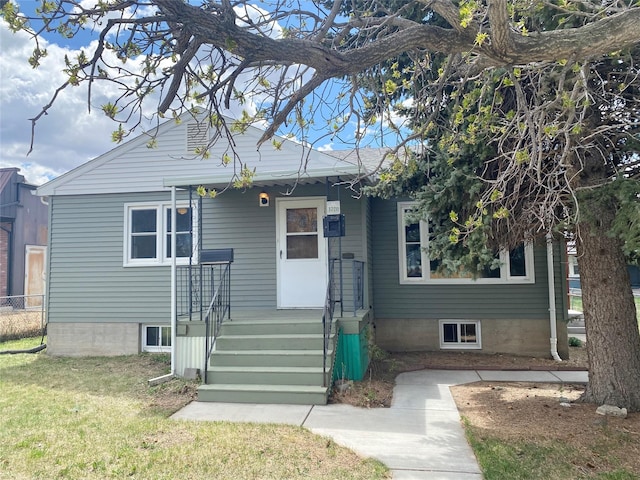 bungalow featuring fence and a front lawn
