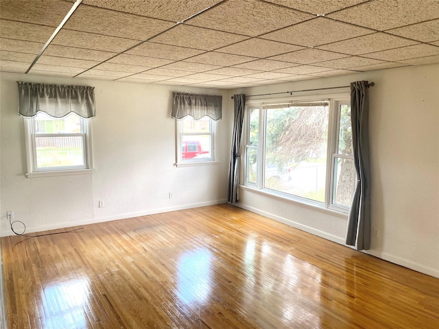 spare room featuring baseboards, a wealth of natural light, and hardwood / wood-style floors