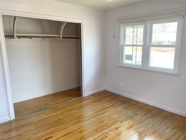 unfurnished bedroom featuring a closet, light wood-style flooring, and baseboards