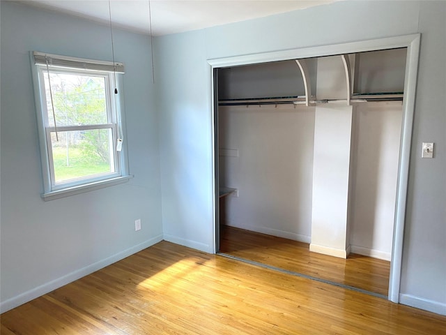 unfurnished bedroom with baseboards, a closet, and light wood finished floors