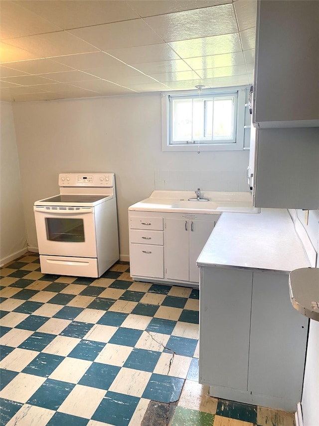 kitchen with light countertops, light floors, electric range, and a sink