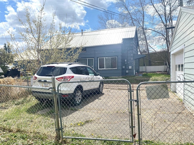 view of side of property with fence, metal roof, and a gate