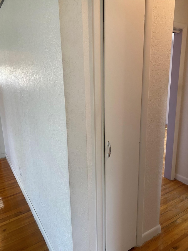 interior details with baseboards, a textured wall, and wood finished floors