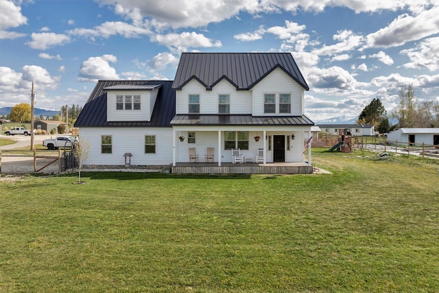 rear view of property with a lawn, fence, a porch, and metal roof