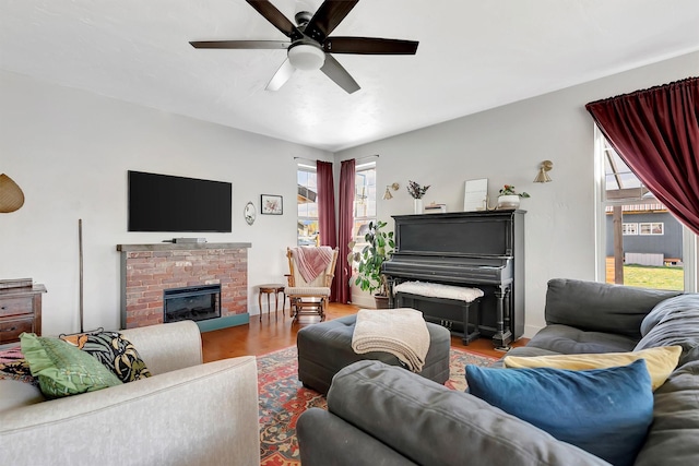 living area with a brick fireplace, a ceiling fan, and wood finished floors
