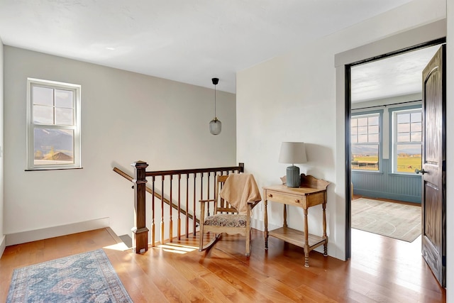 sitting room with baseboards, an upstairs landing, and wood finished floors