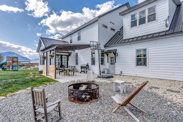685 Hollibaugh Rd, Stevensville, MT 59870 - rear view of house featuring an outdoor fire pit, a standing seam roof, a metal roof, a patio, and a yard