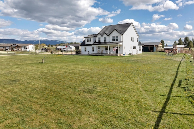 back of property featuring a lawn, fence, and metal roof