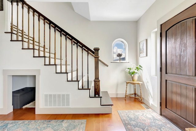 entrance foyer featuring visible vents, stairs, and wood finished floors