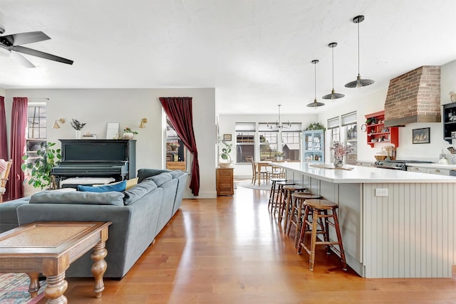 living room with light wood-style floors and ceiling fan with notable chandelier
