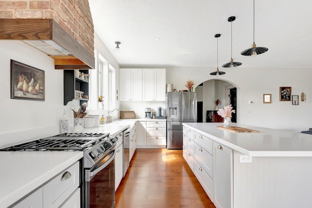 kitchen with arched walkways, a center island, white cabinets, light wood finished floors, and stainless steel appliances