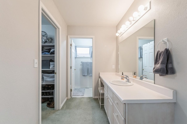 bathroom featuring vanity, baseboards, and a spacious closet