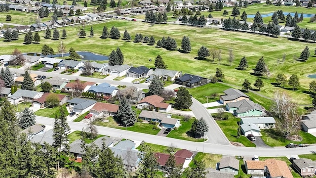 drone / aerial view featuring a water view, view of golf course, and a residential view