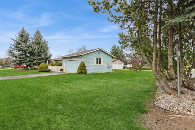 view of side of property with a lawn, driveway, an outbuilding, and a garage