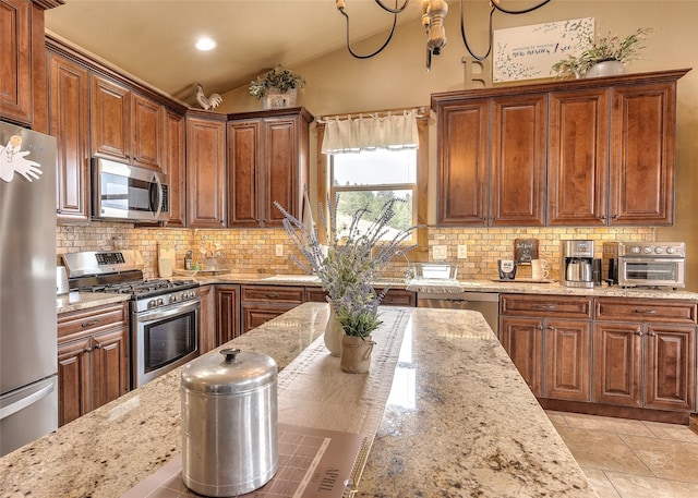 kitchen with light stone counters, appliances with stainless steel finishes, lofted ceiling, and tasteful backsplash