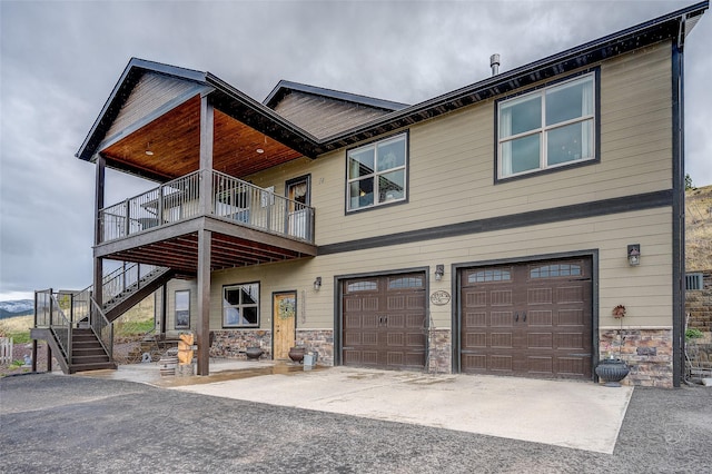 craftsman inspired home with an attached garage, stairs, stone siding, and concrete driveway