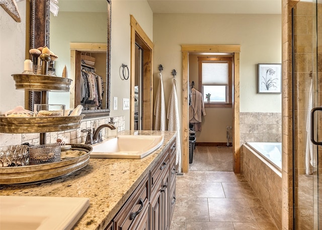 bathroom with double vanity, a sink, tile patterned floors, tiled bath, and tiled shower