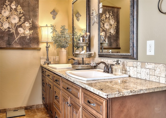 full bathroom featuring double vanity, baseboards, and a sink