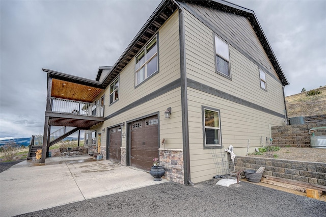 view of property exterior featuring an attached garage, driveway, and stairway