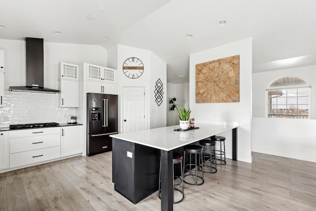 3201 12th St NE, Great Falls, MT 59404 - kitchen with a breakfast bar, wall chimney exhaust hood, black appliances, and light wood-style floors