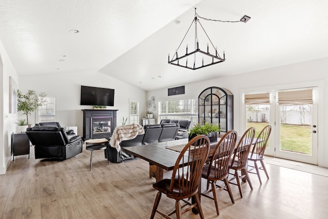 3201 12th St NE, Great Falls, MT 59404 - dining space featuring a glass covered fireplace, an inviting chandelier, lofted ceiling, and light wood-style floors