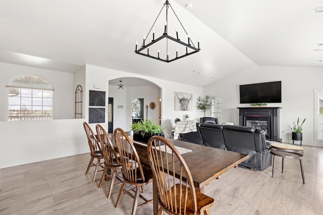3201 12th St NE, Great Falls, MT 59404 - dining area featuring a notable chandelier, arched walkways, a glass covered fireplace, lofted ceiling, and light wood-type flooring