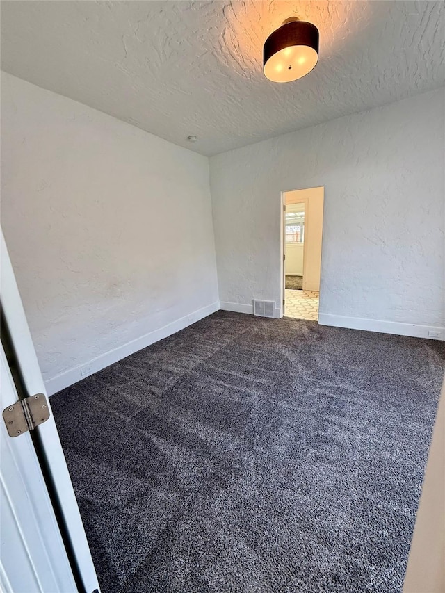 carpeted spare room with visible vents, a textured ceiling, a textured wall, and baseboards
