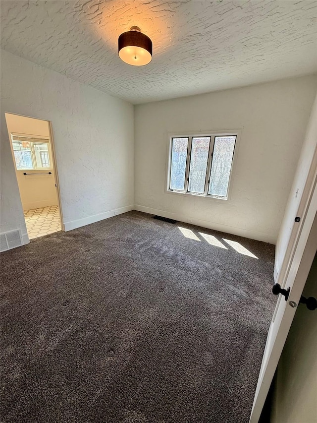unfurnished bedroom featuring a textured ceiling, visible vents, and carpet