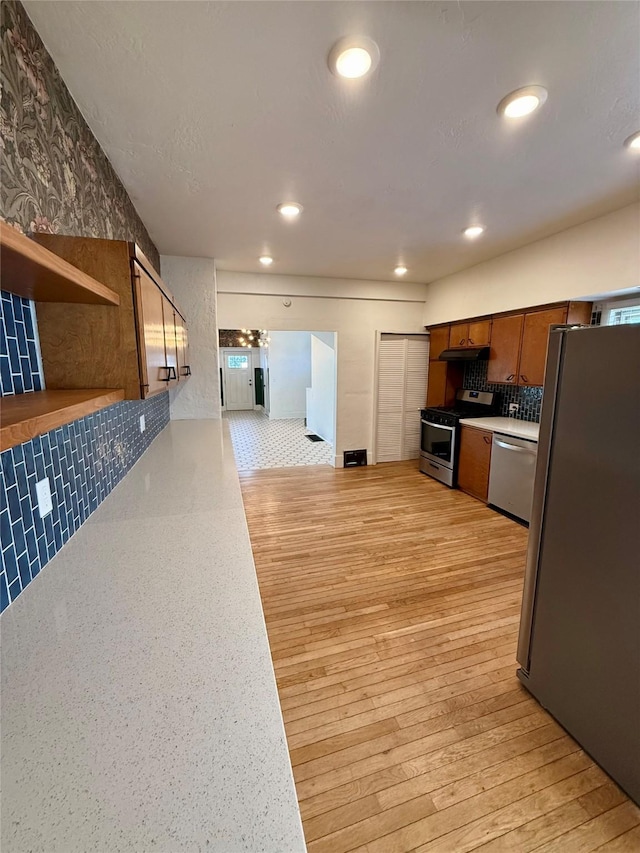 kitchen featuring light wood-type flooring, light countertops, recessed lighting, tasteful backsplash, and stainless steel appliances
