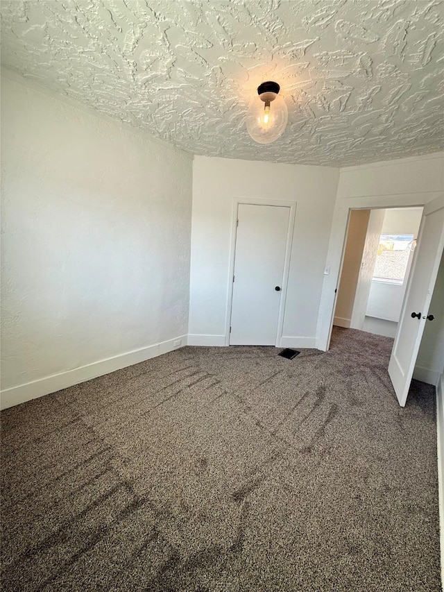 unfurnished bedroom with baseboards, carpet flooring, a textured ceiling, and visible vents