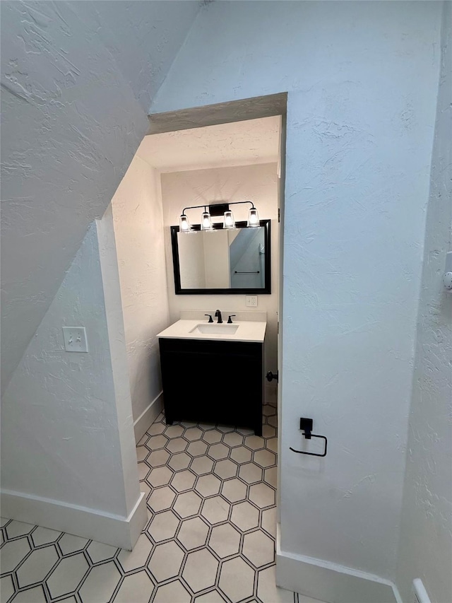 bathroom with vanity, tile patterned flooring, baseboards, and lofted ceiling