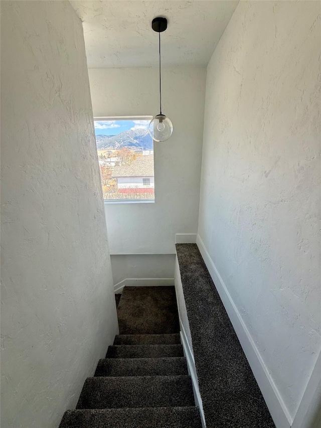 staircase with carpet floors, a textured wall, and baseboards