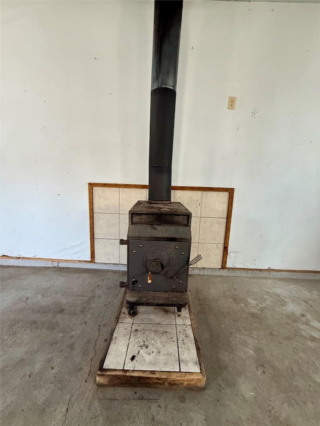 details with a wood stove and unfinished concrete flooring