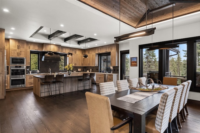 dining space featuring wood ceiling, a towering ceiling, a tray ceiling, recessed lighting, and dark wood-type flooring