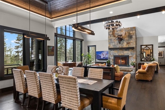 dining area featuring a high ceiling, a notable chandelier, a fireplace, hardwood / wood-style floors, and recessed lighting
