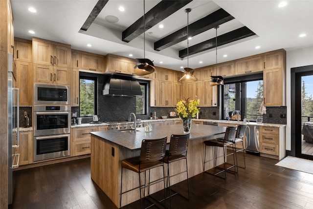 kitchen featuring wall chimney range hood, built in appliances, a tray ceiling, and recessed lighting