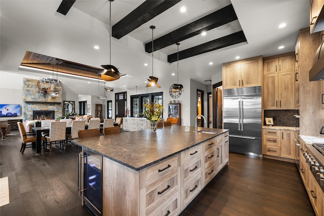 kitchen with light brown cabinetry, dark wood-style flooring, a large island with sink, and stainless steel built in refrigerator