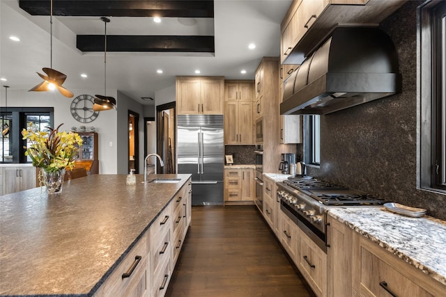 kitchen with light brown cabinetry, a sink, built in appliances, a large island, and custom exhaust hood