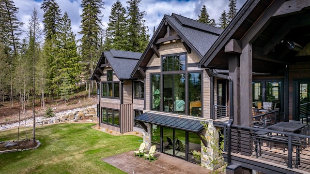 exterior space with a patio, roof with shingles, a yard, and a standing seam roof