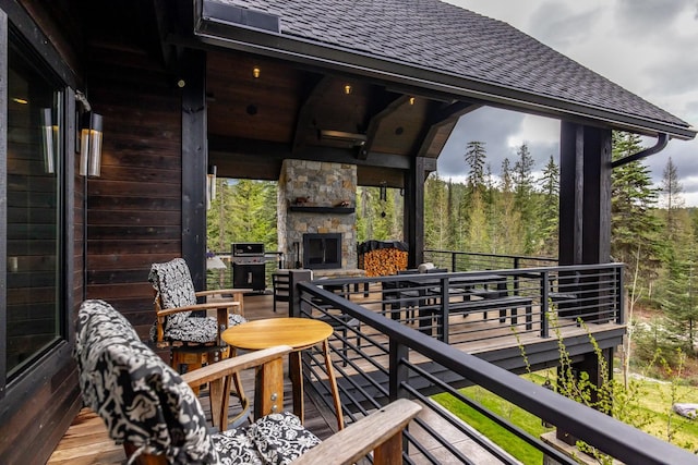 wooden terrace with a grill and an outdoor stone fireplace