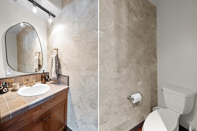 128 River View Dr, Kalispell, MT 59901 - half bath featuring vanity, rail lighting, and backsplash