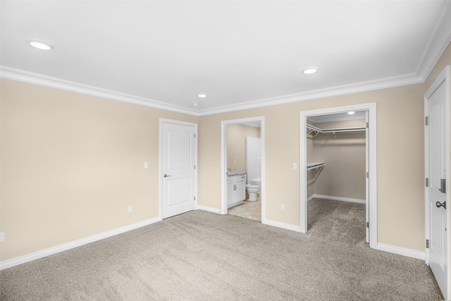 unfurnished bedroom featuring crown molding, baseboards, a walk in closet, and light colored carpet