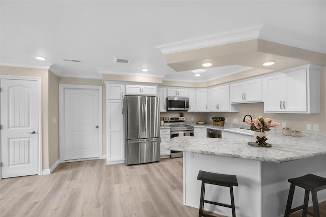 kitchen featuring a breakfast bar, stainless steel appliances, a peninsula, visible vents, and ornamental molding